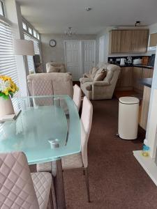 a living room with a glass table and chairs at Grand Chalet 64 Disabled Friendly in Skegness