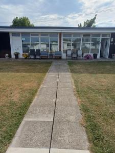 a sidewalk leading to a building with benches on it at Grand Chalet 64 Disabled Friendly in Skegness