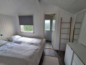 a white bedroom with a bed and a window at Vrensted Hostel B&B in Løkken
