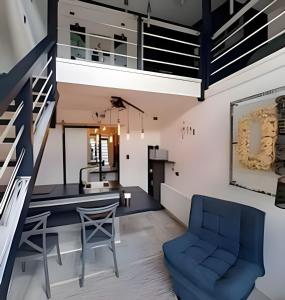 a kitchen and living room with a blue chair and stairs at 2 Family Lofts + central heating + comfort in Coihaique