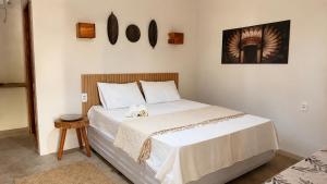 a bedroom with a large bed with white sheets at Vila Maré Alta Caraiva in Caraíva