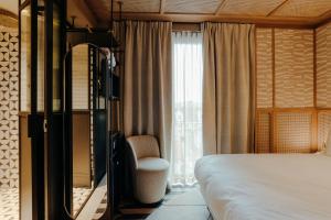 a bedroom with a bed and a chair next to a window at The Diamond Amsterdam in Amsterdam