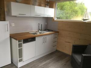 a kitchen with white cabinets and a sink and a window at Houseboat Przystań Spokoju in Ślesin +11 photos