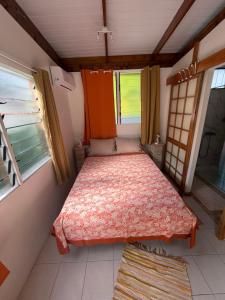 a small bedroom with a bed in a room with windows at Orivai Lodge in Fare