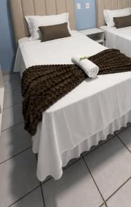 two beds with white sheets and a brown blanket at Pousada Ocean Mare in Praia do Frances +4 photos
