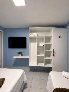 a bedroom with two beds and a tv on a blue wall at Pousada Ocean Mare in Praia do Frances