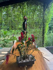 a statue of a bird on a wooden table with flowers at Con Amor Caribe - New 240 sqm Villa & Private Pool in Puerto Viejo