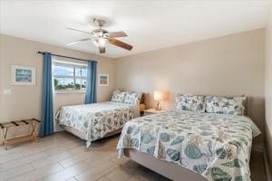 a bedroom with two beds and a ceiling fan at Sea Breeze 101 Beach Bliss in St. Pete Beach