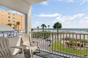 a balcony with two chairs and a view of the beach at Sea Breeze 101 Beach Bliss in St. Pete Beach