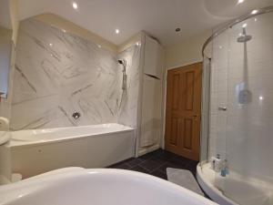 a bathroom with a tub and a shower and a bath tub at The Pearl Manor in Watford