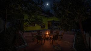 a table with chairs and a fire in front of a house at night at Vanasiri stay inn in Sringeri