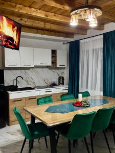 a kitchen with a wooden table and green chairs at Cabana Lavinia Daniel in Statjunea Borsa