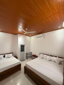 a bedroom with two beds and a wooden ceiling at Yalora Villa Kataragama in Kataragama