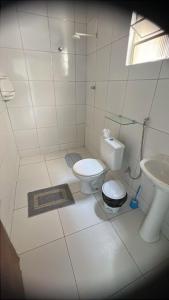 a white bathroom with a toilet and a sink at Caueira Beach House in Itaporanga dʼAjuda
