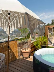 an umbrella on a deck with a bathtub and a bath tub at Dôme Nissaya in Nice