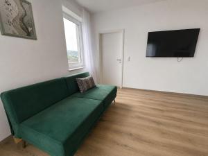 a living room with a green couch and a flat screen tv at Zum Rheinberg Balcony Suite in Braubach