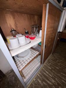 an open refrigerator with bowls and dishes on a shelf at Departamento Monoambiente Rústico in Asunción +10 photos