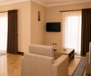a living room with a couch and a chair and a tv at Roadhouse New Cairo Residence in Cairo