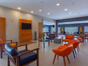 a lobby with chairs and tables and a restaurant at ibis Manaus Distrito Industrial in Manaus