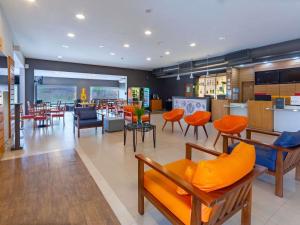 a restaurant with orange chairs and tables in a room at ibis Manaus Distrito Industrial in Manaus