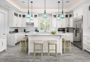 a kitchen with white cabinets and a large island with bar stools at Moringa Villa in Long Bay Hills
