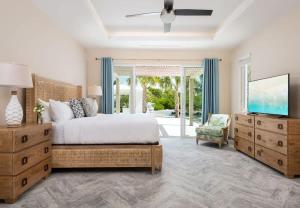 a bedroom with a bed and a tv and a chair at Moringa Villa in Long Bay Hills