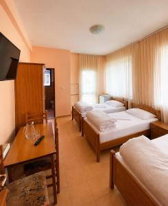 a room with four beds and a table and a tv at Hotel Klajdi in Peshkopi