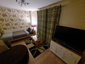 a living room with a couch and a flat screen tv at The Rosewood in Grays Thurrock