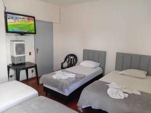 a room with two beds and a flat screen tv at Pousada Central Itabirito in Itabirito