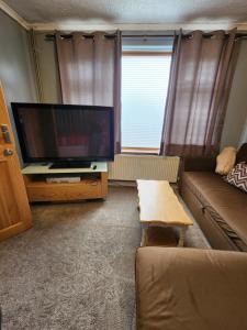 a living room with a flat screen tv and a couch at The Rose in Grays Thurrock