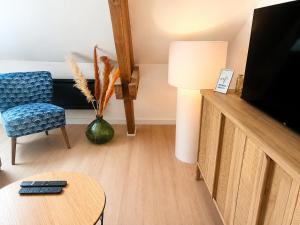 a living room with a tv and a chair and a table at Bel appartement 2 chambres in Ham