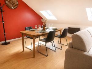 a dining room with a table with chairs and a red wall at Bel appartement 2 chambres in Ham