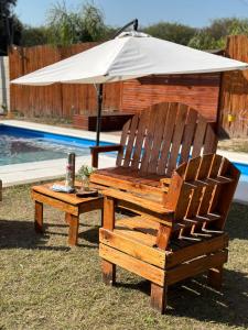 two wooden chairs and an umbrella next to a pool at Finca Alta Gracia La Banda in La Banda