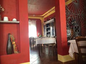 una cucina e una sala da pranzo con pareti rosse e tavolo di I Malpensanti del Trieste a Monticelli dʼOngina