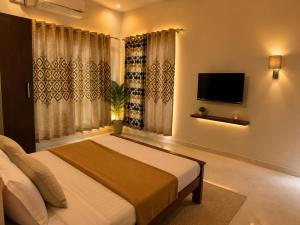 a bedroom with a bed and a tv and curtains at sea stay inn in Mahabalipuram