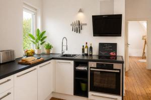 a kitchen with white cabinets and a black counter top at NUJU Rentals - 4-Zimmer, 10 Gäste, Wintergarten & Terrasse & Parkplatz in Bielefeld