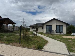 a small white house with a fence in a yard at Chill and Grill Apartments in Wola Smolana