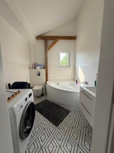 a bathroom with a tub and a washing machine at Chill and Grill Apartments in Wola Smolana