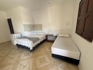 a room with two beds and a mirror on the wall at Hotel Ipê Centro in Barreirinhas