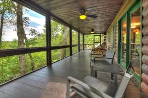 a screened porch with chairs and a ceiling fan at Oscars Outpost Fire Pit Pet Friendly in Mineral Bluff