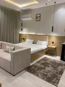 a bedroom with a bed and a couch and a television at لين سويت in Khamis Mushayt