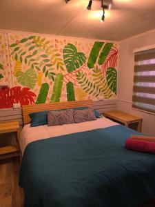a bedroom with a bed with a painting on the wall at Isla Yu Patagonia 2 in Puerto Natales