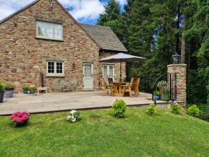 a stone house with a table and an umbrella at Flurry's Lodge in Coleford