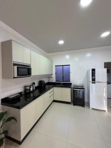 a large kitchen with white cabinets and a refrigerator at Bairro Universtário - Central in Cascavel