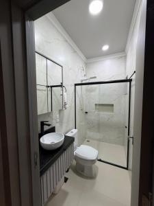 a bathroom with a toilet and a sink and a shower at Bairro Universtário - Central in Cascavel +8 photos