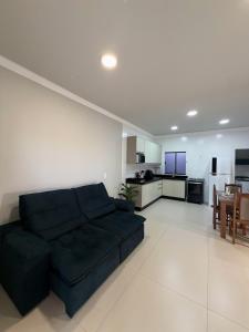 a living room with a black couch and a kitchen at Bairro Universtário - Central in Cascavel