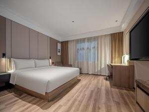 a bedroom with a large white bed and a flat screen tv at Atour Hotel Hefei Hitech Avenue in Hefei