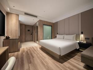 a bedroom with a large white bed and a couch at Atour Hotel Hefei Hitech Avenue in Hefei