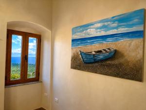 a painting of a boat on a wall next to a window at Ana & Angelo Stone House Vuno Himarë in Vuno +84 photos