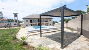 a pergola in front of a house with a swimming pool at Solace Guest house in Buea